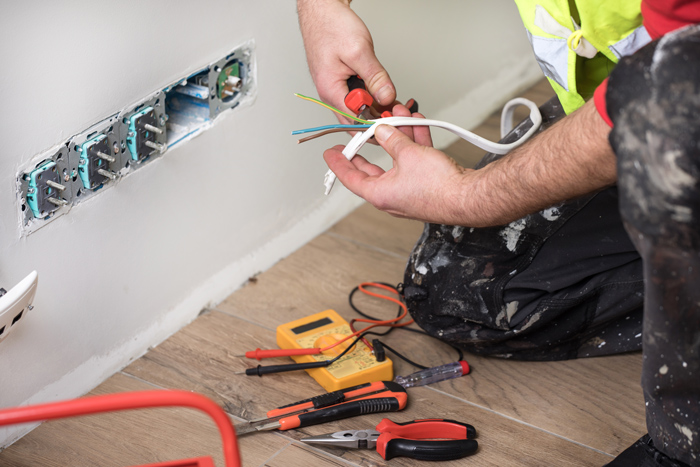 an electrician rewiring a plug socket