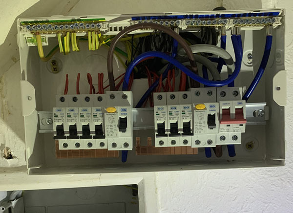 Electrical distribution board with circuit breakers and wiring.