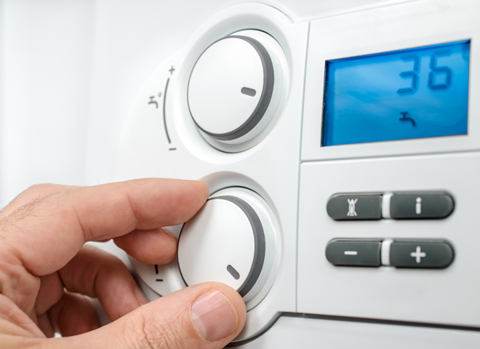 Close-up of a hand adjusting the temperature dial on a digital thermostat, displaying a reading of 36 degrees. Ideal for home heating systems.