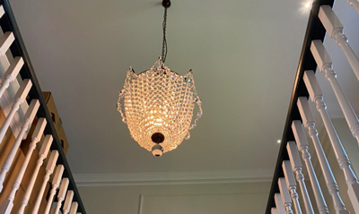 intricately designed chandelier hanging from the ceiling, illuminating a staircase with warm light