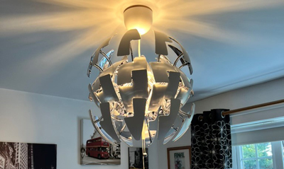 Modern pendant light fixture with a spherical design, featuring white arrows, casting warm light in a living space.