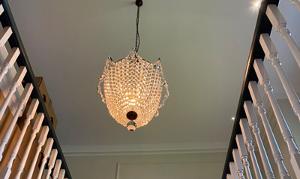 a decorative chandelier hanging from the ceiling, surrounded by vertical wooden beams, illuminating the space with a warm glow